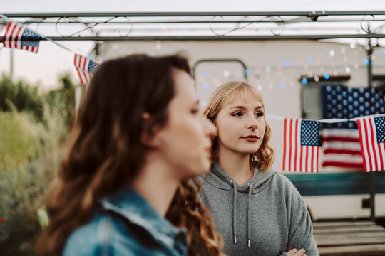 Dos chicas jovenes celebrando día de la independencia de estados unidos con barbacoa frente a una caravana con la bandera americana