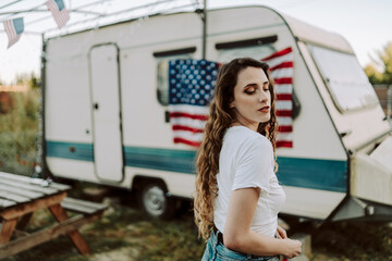 Chica posando y sonriendo frente una caravana con la bandera de estados unidos por el dia 4 de julio