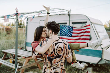 Obraz na płótnie Canvas Pareja de chico y chica juntos besandose con la bandera de estados unidos de fondo en una caravana