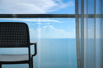 Back view from the window of chair on the balcony, sea and sky background.