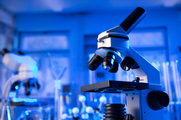 Coronavirus pandemic theme. Science research concerning fast covid tests and anti-covid vaccine. Microscope, beakers and test tubes in the scientific laboratory.
