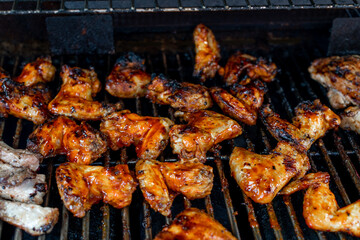 Bbq chicken wings on a barbecue grill cooking with a nice chargrilled finish, shallow depth of field advertising image