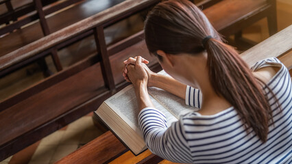 Christian woman praying on holy bible in the public church. Woman pray for god blessing to wishing...