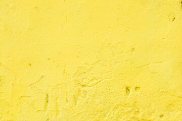 A fragment of an old wall with rough, bright yellow plaster.