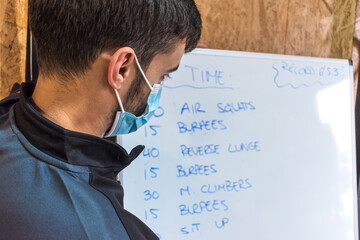Personal trainer writing exercise chart on a whiteboard