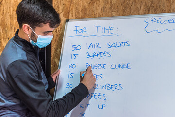 Personal trainer writing exercise chart on a whiteboard