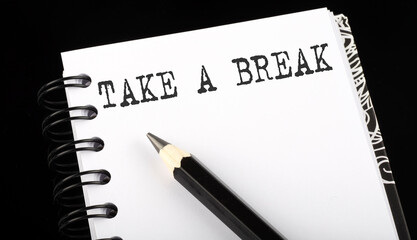 TAKE A BREAK written text in small notebook on a black background