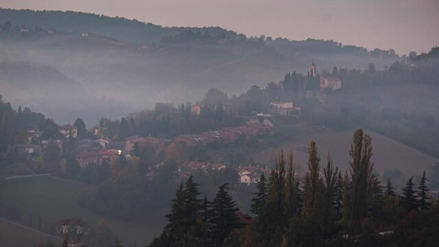 Blue hour time lapse of a small town in a valley and a smoke cloud moving, Emilia Romagna, Italy, Europe
