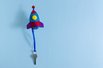 Flying up felt rocket toy with a key on a string on a blue background. The creative concept of...