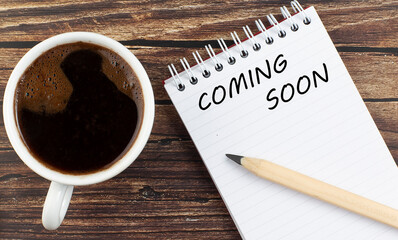 COMING SOON text on notebook with coffee on wooden background
