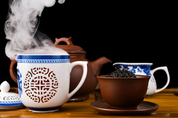 Chinese tea ceremony. Clay teapot with red tea Lapsang souchong and cup of hot tea with vapour...