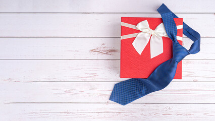 Fototapeta na wymiar Happy Father's Day with a blue tie and a gift box on wooden background with space for text. Top view. Flat lay