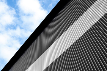 Fototapeta na wymiar Black and white corrugated iron sheet used as a facade of a warehouse or factory. Texture of a seamless corrugated zinc sheet metal aluminum facade. Architecture. Metal texture.