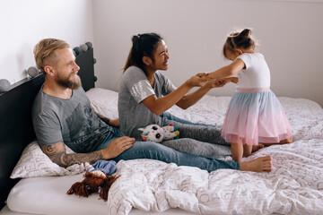 Family playing at home on the bed in the bedroom