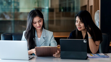 Charming Asian businesswoman brainstorming collaboration using documents and a laptop computer at the office.