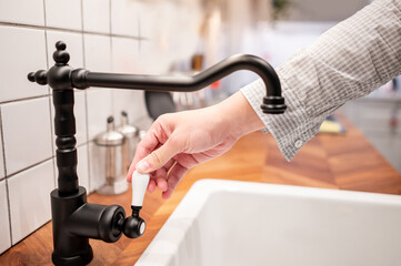 Male hand opening retro water tap in the kitchen. Home improvement for domestic kitchen.