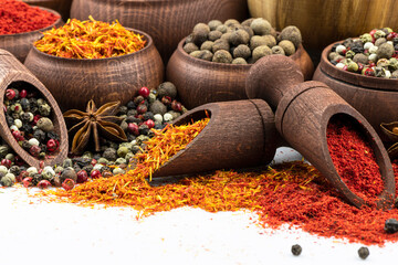 An assortment of spices in wooden dishes on a white background.