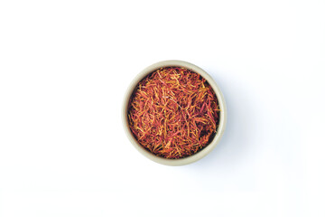 Saffron spices threads in heart shaped plate isolated on white background. Top view. Saffron flavor and coloring seasoning ingredient.