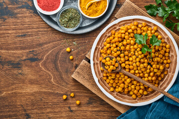 Fried chickpeas with turmeric in ceramic plate on an old wooden table background. Roasted spicy chickpeas or Indian chana or chole, popular snack recipe. Top view.