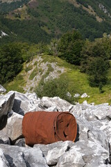 Environmental pollution. Old rusty barrel abandoned in the stony ground.On the mountains of the...