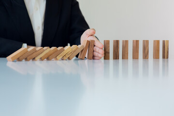Businesswoman protect wooden block fall to planning and strategy in risk to business Alternative...