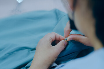 Female tailor hands sewing fabric cloths on the textile industry