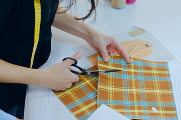 Closeup shot of a worker cutting a piece of fabric in a textile factory