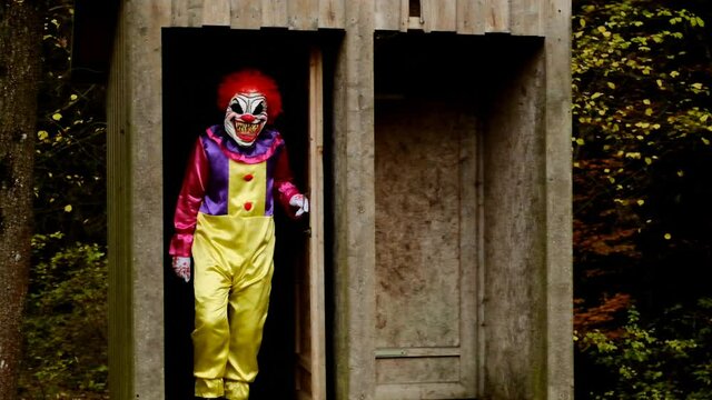 Halloween.Aggressive scary clown. Evil clown attacks.Halloween.Scary clown running in autumn park.  horror concept.