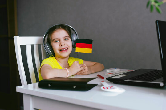 Cute Girl Kid 6-7 y.o. is Learning a Foreign Language Remotely Online via a Laptop. German language and culture of Germany.