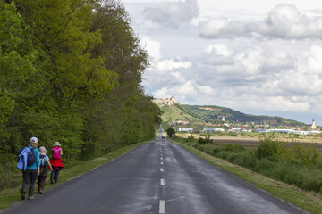 eine familie wandert auf der Landstrasse in Richtung einer Stadt