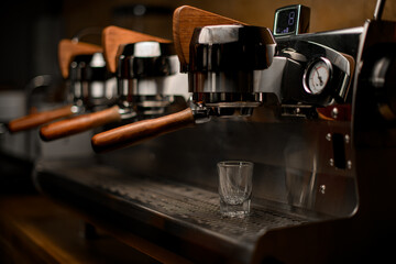 empty glass on steel surface of professional coffee machine in coffee shop
