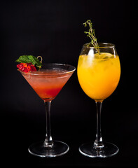 multicolored cocktails decorated with fruits with ice on a black background