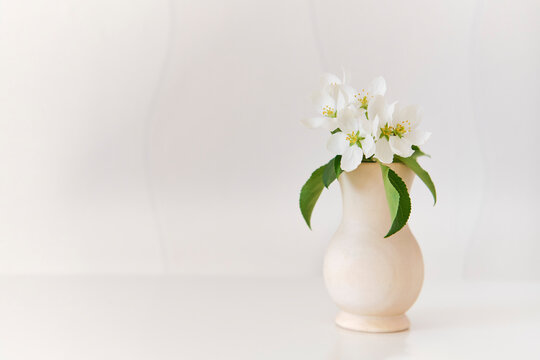 A beautiful a sprig of apple tree with white flowers in a wood vase