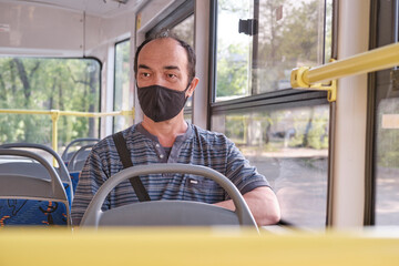 Portrait of senior Asian man wearing a black protective face mask in public transport.