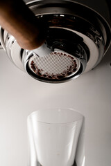 close-up view on portafilter of coffee machine through which droplets of hot coffee flow