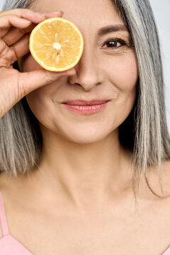 Beauty. Portrait Of Middle Aged Beautiful Asian 50s Woman With Perfect Glow Radiant Skin Holding Citrus Juicy Lemon Fruit. Vitamin C Antioxidants Cosmetics Whitening Care Treatment Advertising Concept