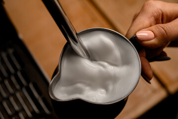 Close-up view of fresh whipped foam of cream in jug in woman's hand