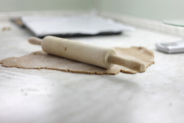 Closeup shot of a wood rolling pin and dough on the table