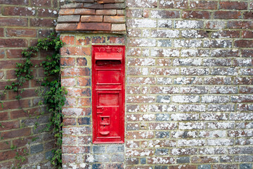 Old disused typical red English postbox on the wall of a house