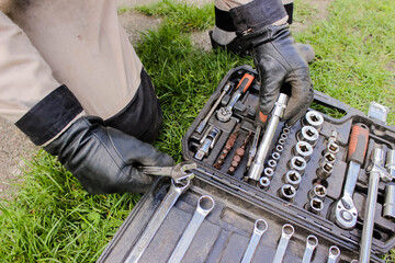 Male hand in construction of a glove with a ratchet taken from a toolbox. Industrial metal tool