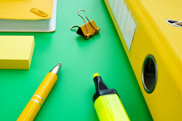 Yellow pen, folder and notepad on the green background. Paperwork and office supplies.