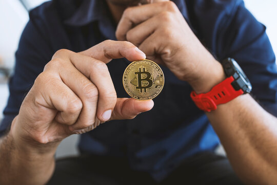 Golden Bitcoin In A Businessman Hand In The Office With Soft Focus And Backlighting. Cryptocurrency Concept