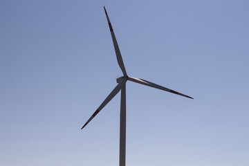 Close up view of windmill in Sigacik / Seferihisar district of Izmir / Turkey. Wind power turbine for clean, renewable energy. Sustainability concept. It is a sunny summer day.