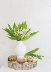 lily of the valley in vase on background old white wall