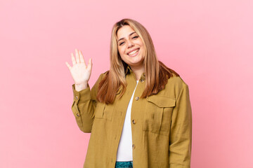 curvy pretty blonde woman smiling happily, waving hand, welcoming and greeting you © kues1