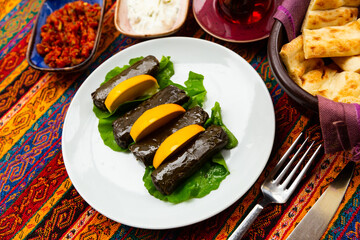 Traditional Turkish sarma from vine leaves filled with rice served with lime and greens. Authentic...