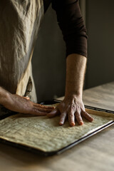 Male hands spreading the dough on a baking sheet