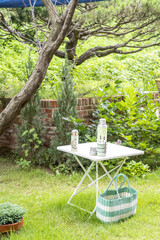 Vertical shot of a cute little white outdoor table under a tree in a garden in the sunshine