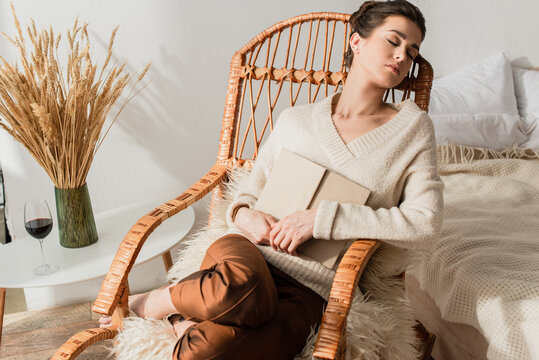 Young Woman Sleeping In Rocking Chair With Book