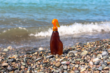 Fototapeta na wymiar Sun tanning spray bottle at the sea coast on a sunny day. Idea for mock up and advertisement for summer